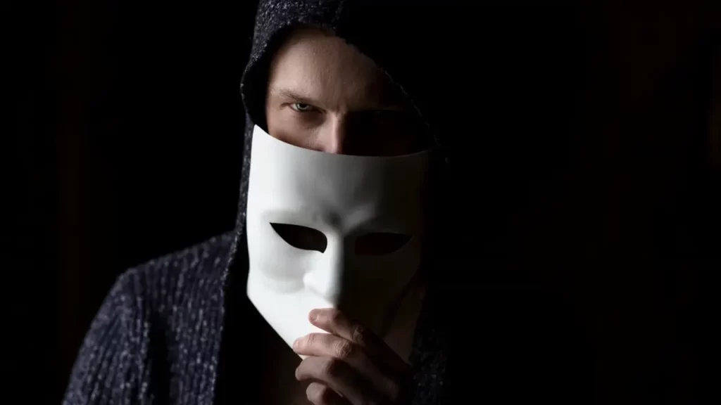 A man revealing his face under a mask. Illustrates morally gray BBEG.