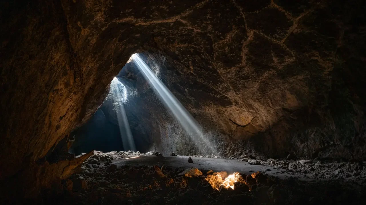 a-light-shines-through-the-opening-of-a-cave A light shines through the opening of a cave. Themes of the Raiders Principle.