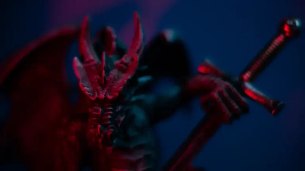 A close up photograph of a dragon miniature holding a sword. Themes of 2024 Dungeon Master's Guide.