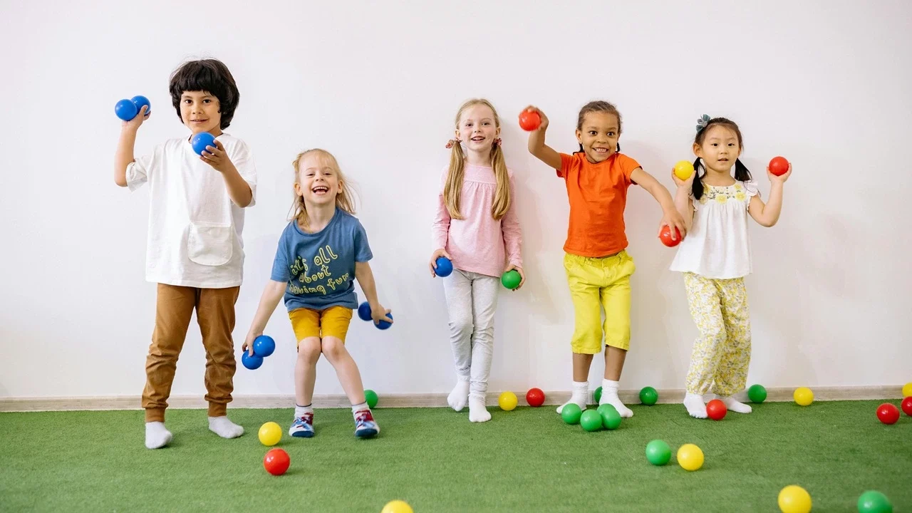 Five children against a wall throwing toys