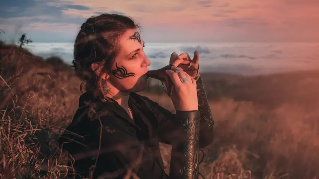 A woman standing in a field holding an ocarina.
