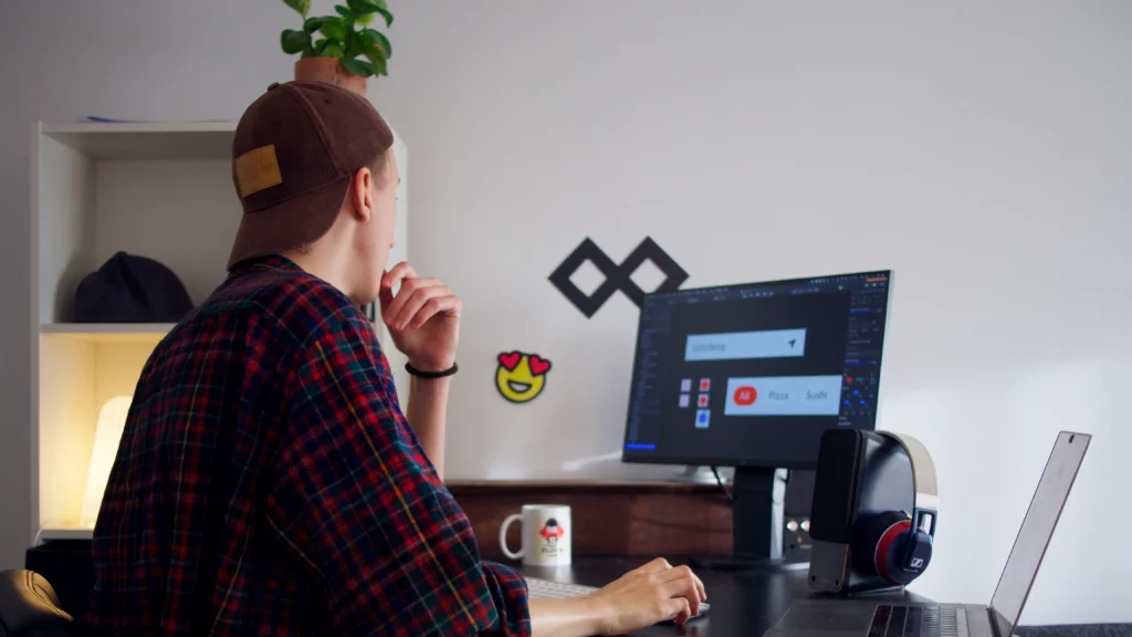 A photo of a man sitting near a table using the computer. Themes of client's end product.