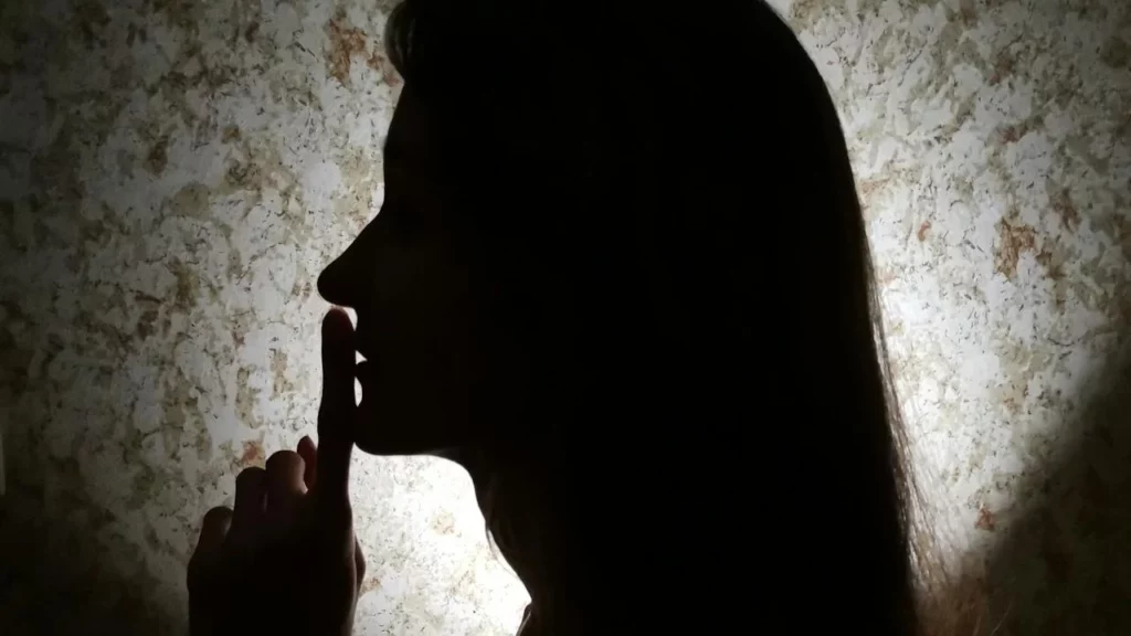 Photo of a woman wanting to use silence in a dark room.
